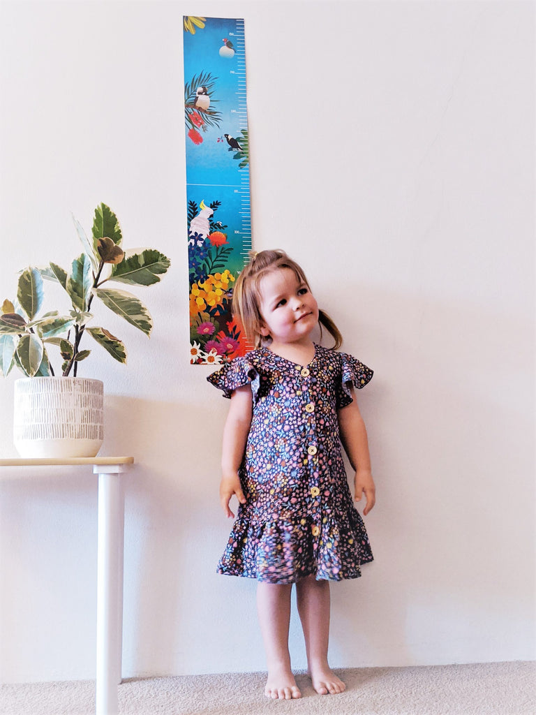 4 years old girl Juliette standing beside an australian bush height chart on the wall
